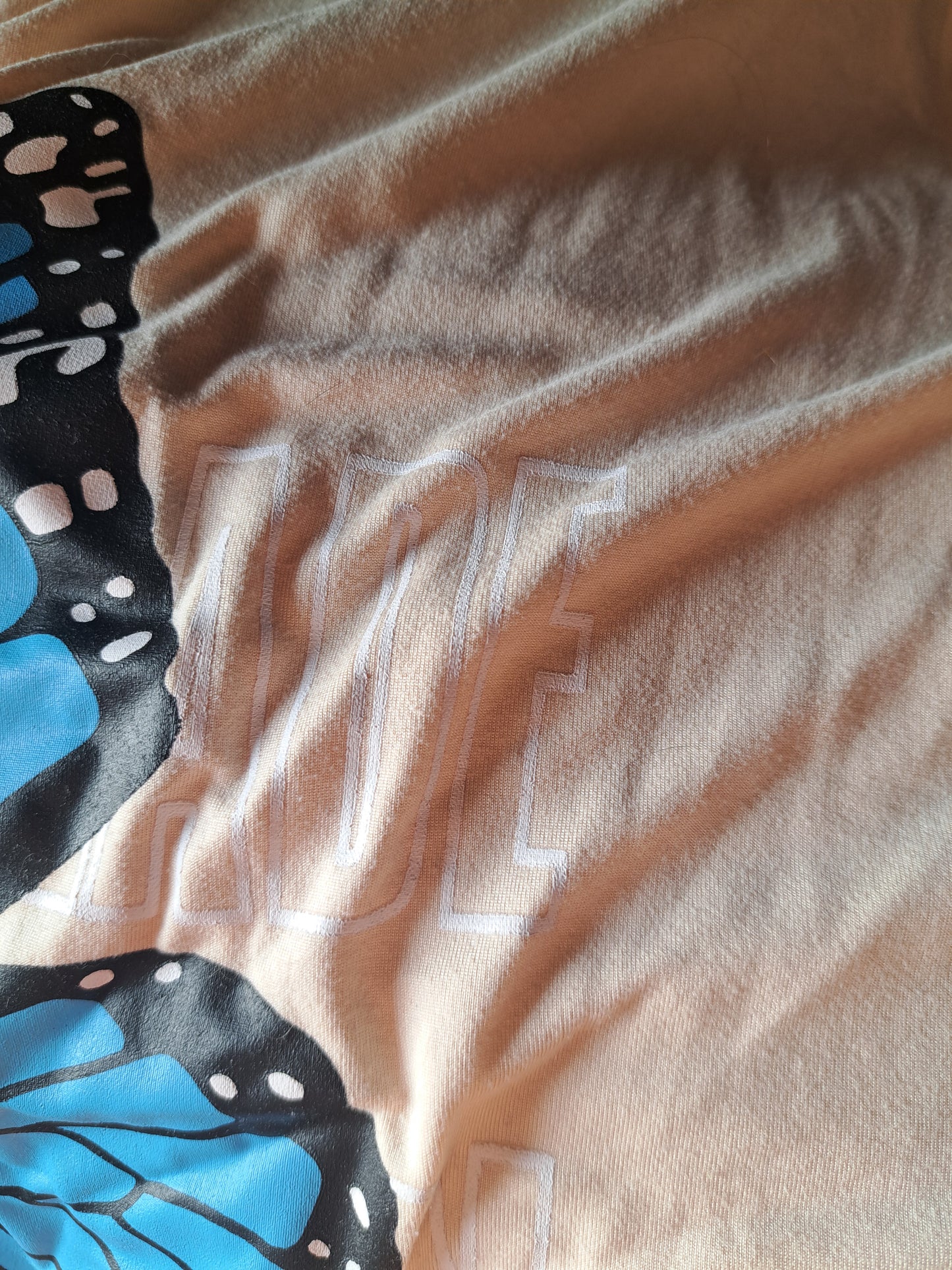 T-shirt beige avec papillon bleu